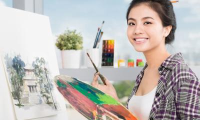 Student artist smiling with paint brush and paint palette